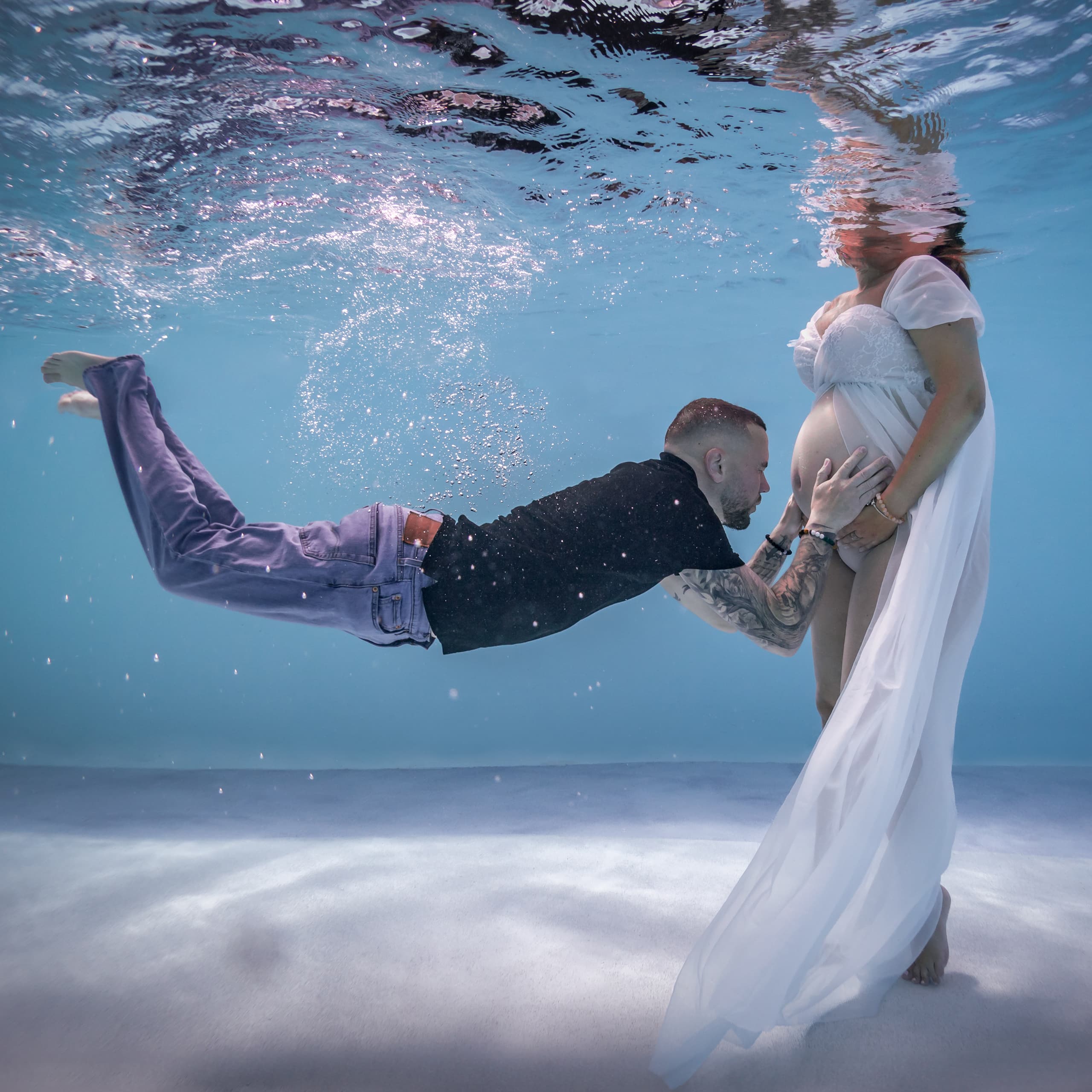 Photo de couple prise durant une séance grossesse aquatique. ©Maxime Bonneau, Nautile Photographie 2023.