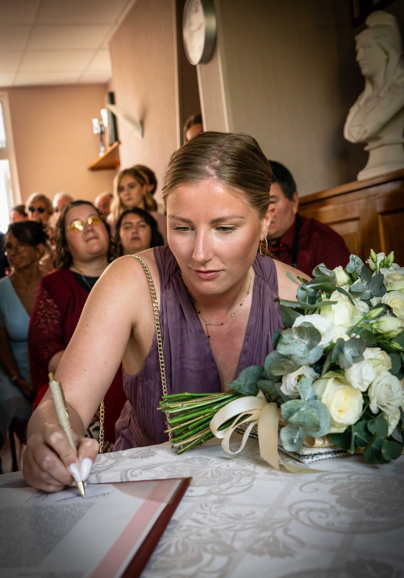 La témoin de la mariée signe le certificat de mariage lors de la cérémonie civile. Photographe de mariage : ©Maxime Bonneau, Nautile Photographie 2023.