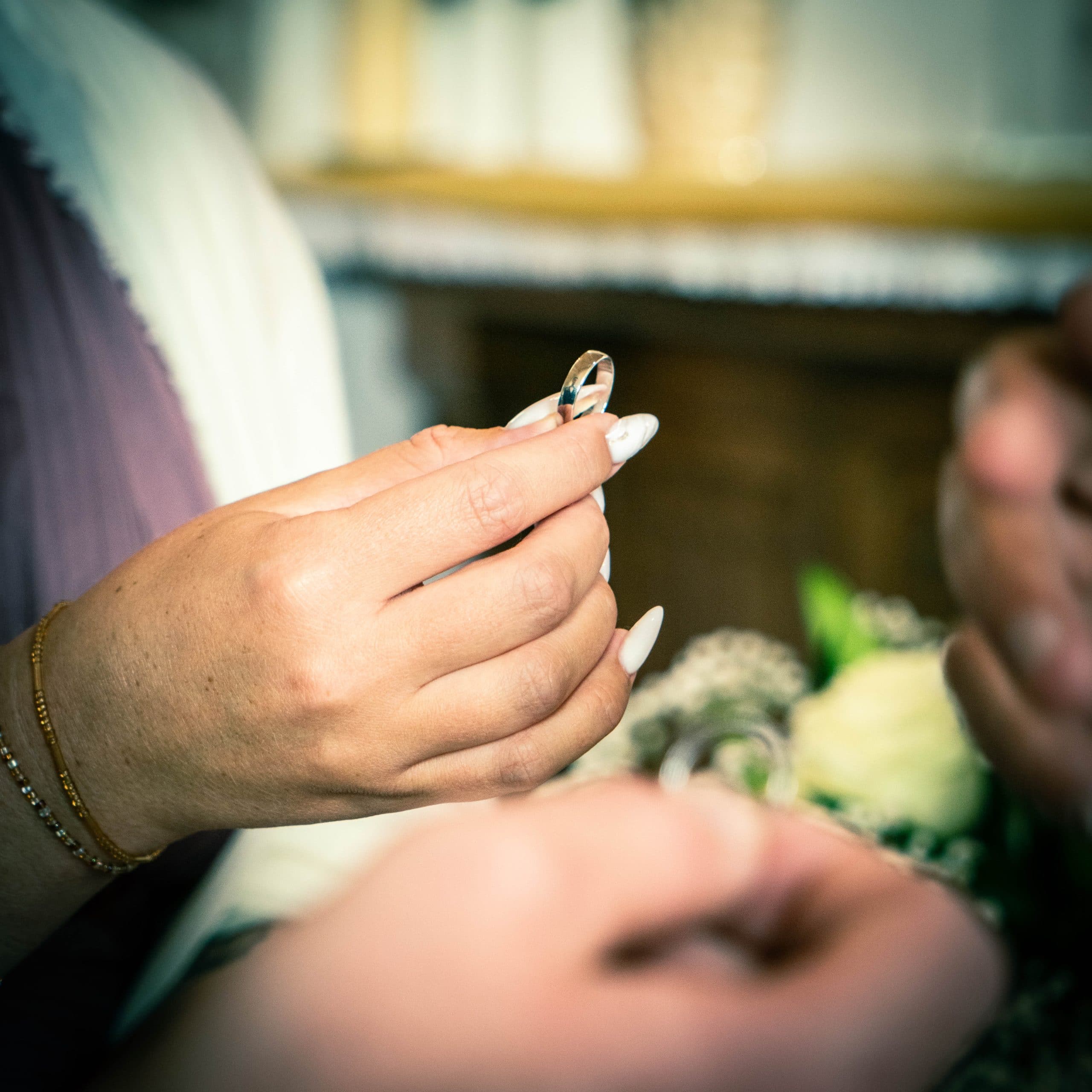 La témoin de la mariée tient l'alliance pendant la bénédiction. Photographe de mariage : ©Maxime Bonneau, Nautile Photographie 2023.